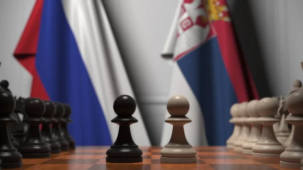 Drapeaux de la Russie et de la Serbie derrière pions sur l'échiquier. Jeu d'échecs ou rivalité politique liée au rendu 3D — Photo