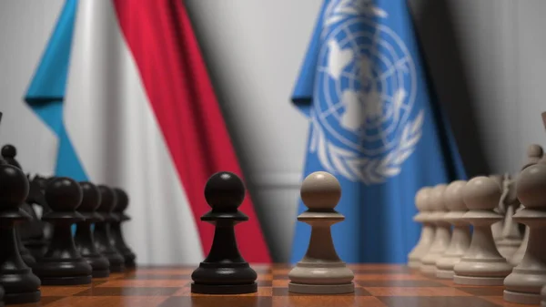 Luxemburg és az Egyesült Nemzetek zászlói gyalogok mögött a sakktáblán. Fogalmi szerkesztői 3d renderelés — Stock Fotó