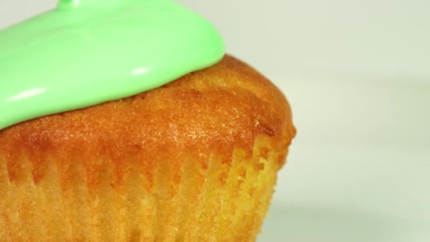 Grüne Glasur über Muffin gießen, Makroaufnahme auf Rot — Stockvideo