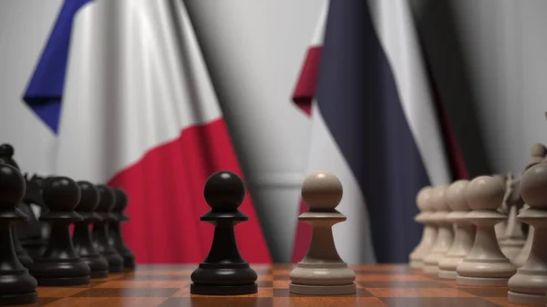 Bandiere di Francia e Thailandia dietro pedoni sulla scacchiera. Rendering 3D relativo alla partita a scacchi o alla rivalità politica — Foto Stock