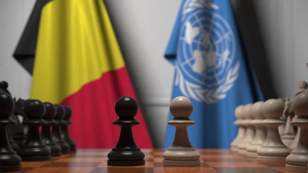 Прапори Бельгії та Організації Об'єднаних Націй за пішаками на шаховій дошці. Шахова гра або політичне суперництво пов'язують 3d рендеринг — стокове фото