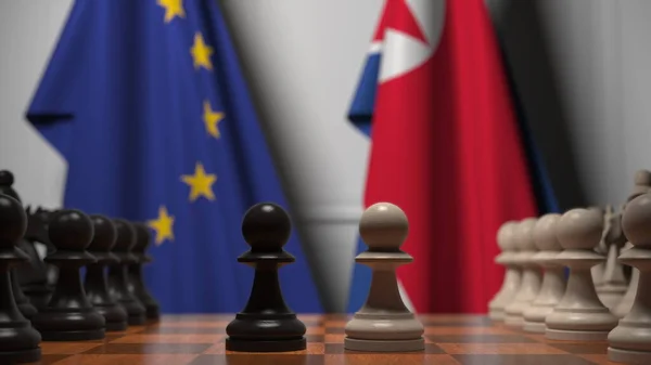 Drapeaux de l'UE et de la Corée du Nord derrière des pions sur l'échiquier. Jeu d'échecs ou rivalité politique liée au rendu 3D — Photo