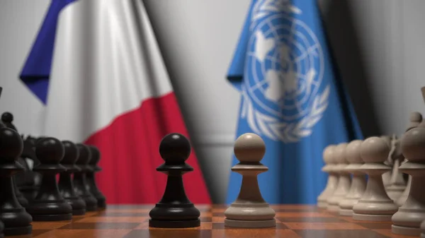 チェスボード上の質屋の後ろにフランスと国連の旗。チェスゲームや政治的ライバル関係の3Dレンダリング — ストック写真