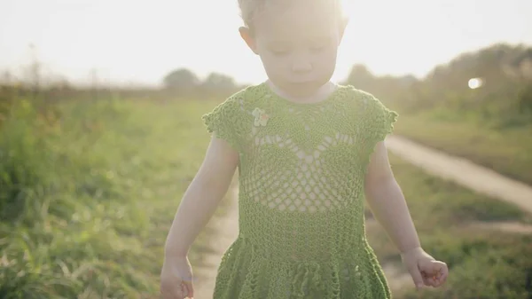 Una bambina sconvolta cammina lungo il sentiero del campo in una giornata di sole — Foto Stock