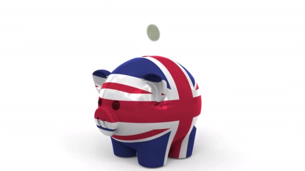 As moedas caem no banco piggy pintado com a bandeira da Grã-Bretanha. Sistema bancário nacional ou animação conceitual 3D relacionada com poupança — Vídeo de Stock