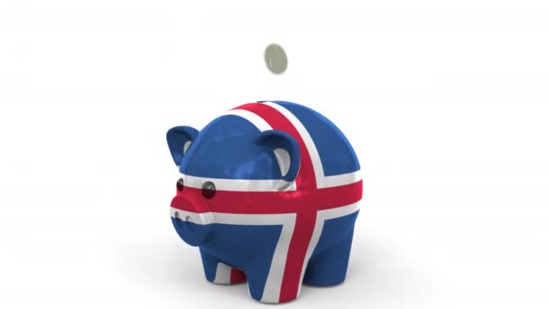 Монеты попадают в копилку, расписанную флагом Исландии. Национальная банковская система или связанная с ней концептуальная 3D анимация — стоковое видео