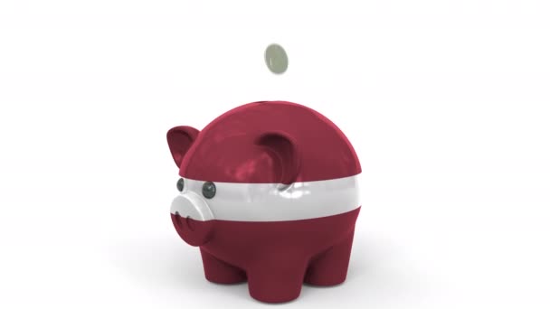 Coins fall into piggy bank painted with flag of Latvia. National banking system or savings related conceptual 3D animation — Stockvideo