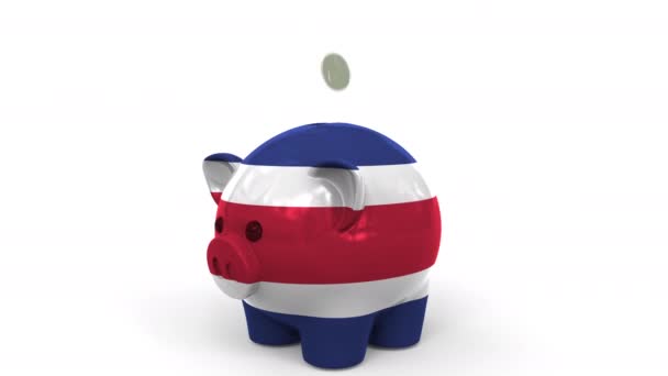 Münzen fallen in Sparschweine, die mit der Flagge Costa Ricas bemalt sind. Nationales Bankensystem oder Ersparnisse bezogene konzeptionelle 3D-Animation — Stockvideo