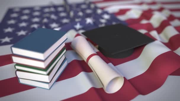 Klobouk, knihy a diplom na americké vlajce. Vysokoškolské vzdělání v konceptuální 3D animaci související s USA — Stock video