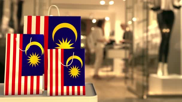 Torebki na zakupy z flagą Malezji przeciwko zamazanemu sklepowi. Malezyjski klip na zakupy — Wideo stockowe