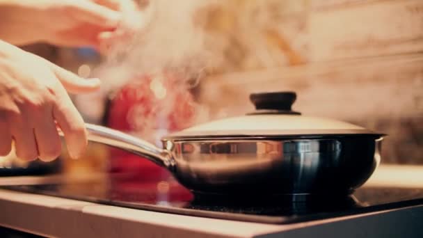 Het openen van hete sissende stalen pan op fornuis top. Koken thuis — Stockvideo