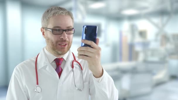 Erkek doktor bir hastayla teletıp görüntülü konuşma için telefonunu kullanıyor. — Stok video