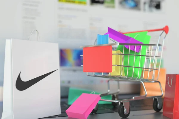 Papírzacskó Nike logóval és bevásárlókocsival egy laptop billentyűzetén. Szerkesztői online vásárlás kapcsolódó 3D-s renderelés — Stock Fotó