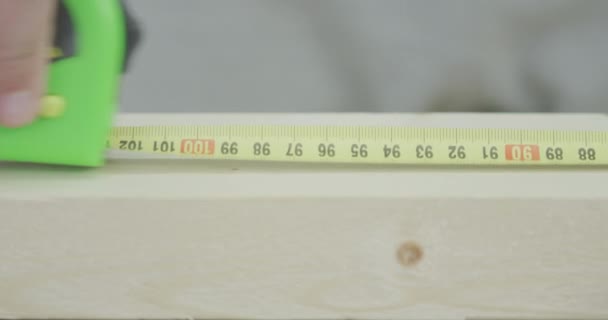 Homem usa fita régua para marcar o tamanho da prancha de madeira, DIY ou fazê-lo sozinho relacionados close-up tiro em câmera lenta no vermelho — Vídeo de Stock