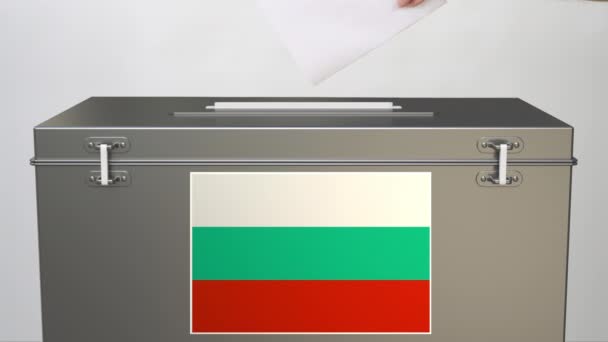 Mano poniendo papeleta de papel en las urnas con bandera de Bulgaria. Clip relacionado con elecciones — Vídeos de Stock