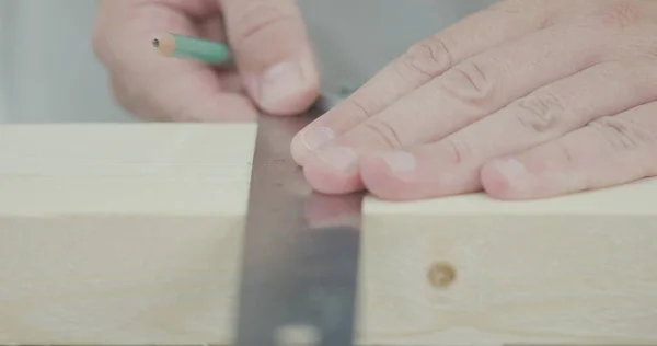 Mann benutzt eisernes Lineal, um Holzplankengröße zu markieren — Stockfoto