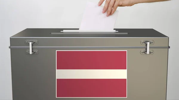 Mise à la main du bulletin de vote en papier dans l'urne avec drapeau de la Lettonie. Rendu 3d lié aux élections — Photo