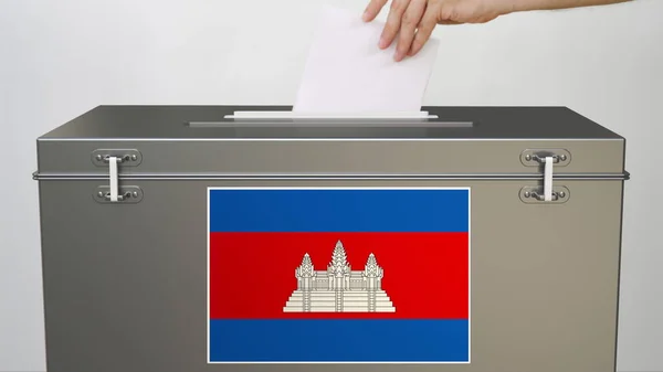 Рука кладет бумажный бюллетень в урну для голосования с флагом Камбоджи. 3D-рендеринг выборов — стоковое фото