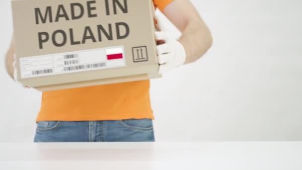 L'homme met une boîte en carton avec du texte MADE IN POLAND sur la table — Video