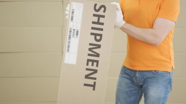 Magazijnmedewerker met groot pakket met bedrukte SHIPMENT tekst en etiket erop — Stockvideo