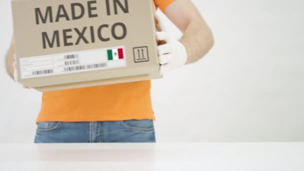 Ο άνθρωπος βάζει χαρτονένιο κουτί με κείμενο MADE IN MEXICO στο τραπέζι — Αρχείο Βίντεο