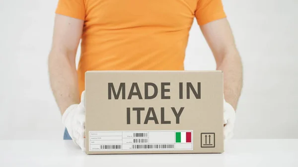 Мужчина кладет на стол картонную коробку с текстом MADE IN ITALY — стоковое фото