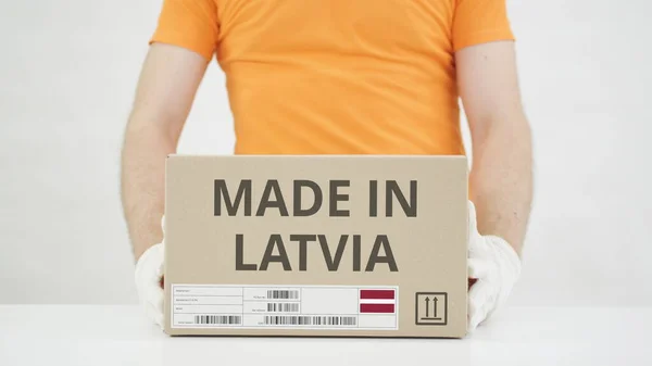 Чоловік кладе картонні коробки з MADE в LATVIA текст на стіл. — стокове фото