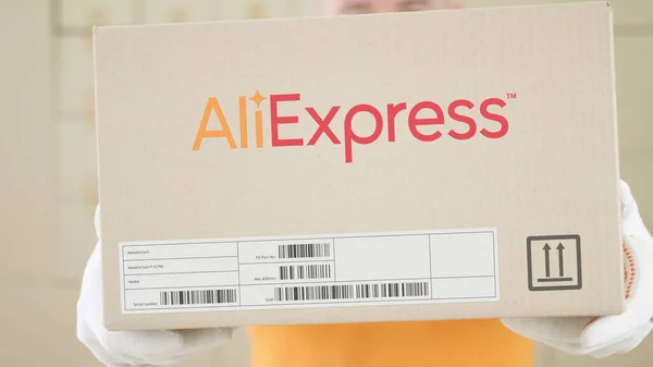 Il lavoratore del magazzino tiene la scatola con il logo ALIEXPRESS stampato su di essa. Colpo concettuale editoriale — Foto Stock