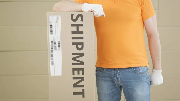 Üzerinde SHIPMENT yazılı metin ve etiket olan büyük bir paket ile depo çalışanı — Stok fotoğraf