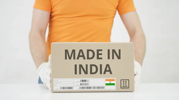 El hombre pone una caja de cartón con texto MADE IN INDIA sobre la mesa —  Fotos de Stock