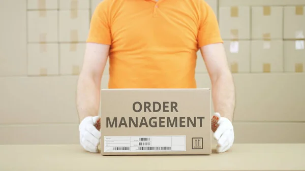 Homem coloca caixa com texto de gestão de pedidos na mesa — Fotografia de Stock