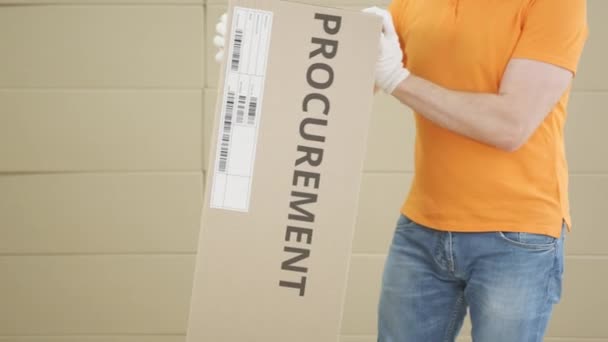 Ouvrier d'entrepôt avec grand colis avec texte imprimé de PASSATION DU MARCHÉ PUBLIC et étiquette dessus — Video