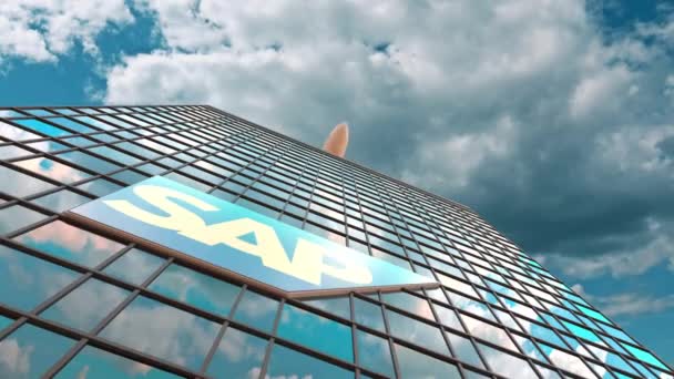 SAP SE логотип на сучасному хмарочосі, що відображає хмари і літаючий літак. Редакційна концептуальна 3D анімація — стокове відео