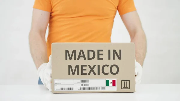 El hombre pone una caja de cartón con texto MADE IN MEXICO sobre la mesa —  Fotos de Stock