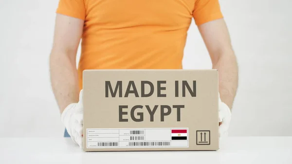 El hombre pone una caja de cartón con texto MADE IN EGYPT sobre la mesa —  Fotos de Stock
