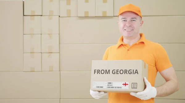 Trabajador de almacén sostiene paquete con texto de GEORGIA en él — Foto de Stock