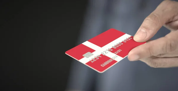 Ο άνθρωπος δίνει πιστωτική κάρτα με τυπωμένη σημαία της Δανίας. Φανταστικοί αριθμοί — Φωτογραφία Αρχείου
