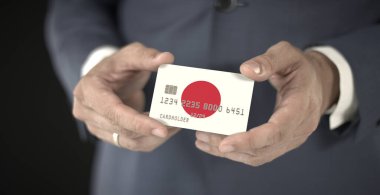 Businessman holds plastic bank card with printed flag of Japan, fictional numbers clipart