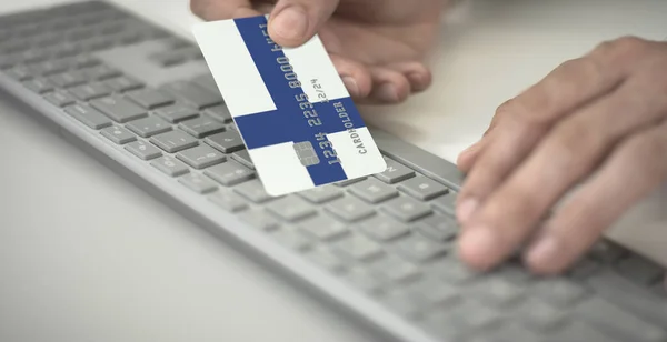 El hombre paga en línea con tarjeta bancaria de plástico con la bandera impresa de Finlandia. Números de ficción — Foto de Stock