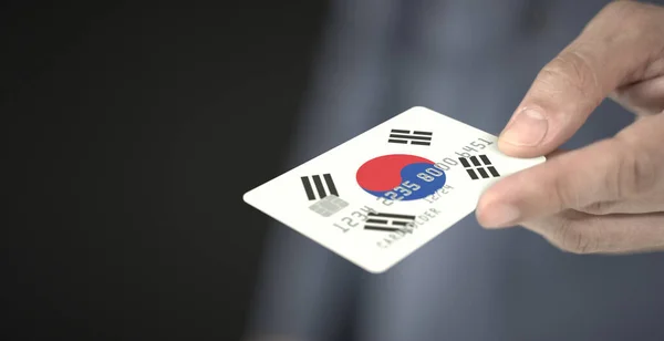 Unbekannter bietet Plastikbankkarte mit aufgedruckter Flagge Südkoreas an. Fiktive Zahlen — Stockfoto