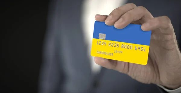Επιχειρηματίας κρατώντας πλαστική τραπεζική κάρτα με τυπωμένη σημαία της Ουκρανίας στα χέρια του, φανταστικούς αριθμούς — Φωτογραφία Αρχείου