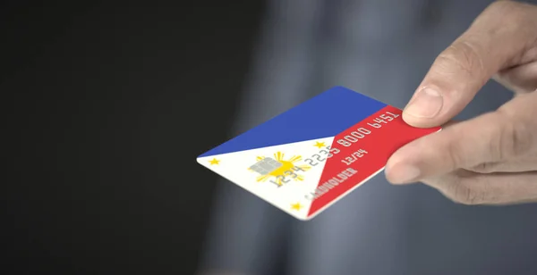 Orang tak dikenal memberikan kartu bank plastik dengan bendera cetak Filipina. Bilangan Fiksional — Stok Foto