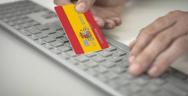 Homem paga online com cartão bancário de plástico com bandeira impressa da Espanha. Números fictícios — Fotografia de Stock