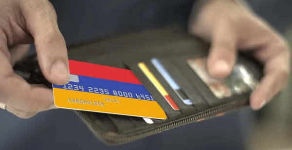 Un homme sort de son portefeuille une carte bancaire en plastique avec le drapeau de l'Arménie, un numéro de carte fictif — Photo