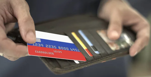 Ο άνθρωπος βγάζει την πιστωτική κάρτα με τη σημαία της Ρωσίας από το πορτοφόλι του, αριθμός πλασματικής κάρτας — Φωτογραφία Αρχείου