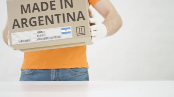 Man zet kartonnen doos met MADE IN ARGENTINA tekst op tafel — Stockvideo