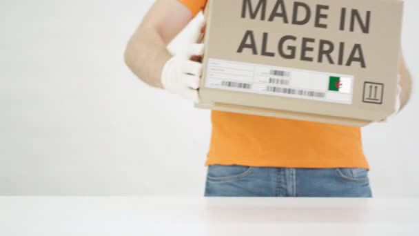 Muž položí kartónovou krabici s textem MADE IN ALGERIA na stůl — Stock video