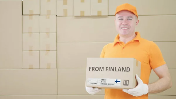 Trabajador de almacén sostiene paquete con texto de FINLANDIA en él — Foto de Stock