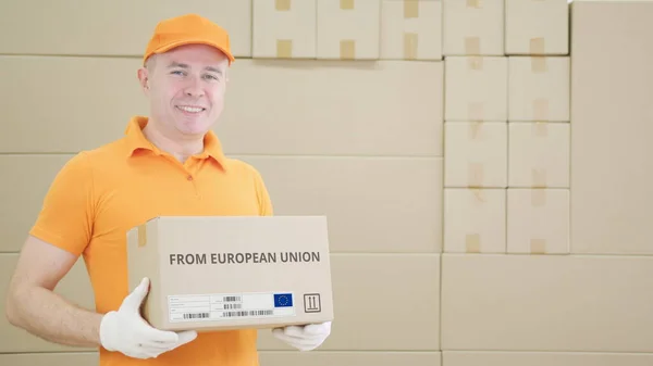 Man holding cardboard parcel with print of EUROPEAN UNION text on it — Stok Foto