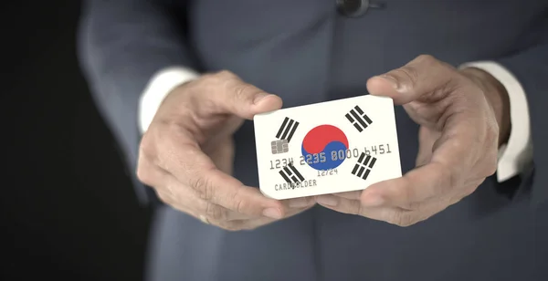Empresário com cartão de banco de plástico com bandeira impressa da Coreia do Sul, números fictícios — Fotografia de Stock
